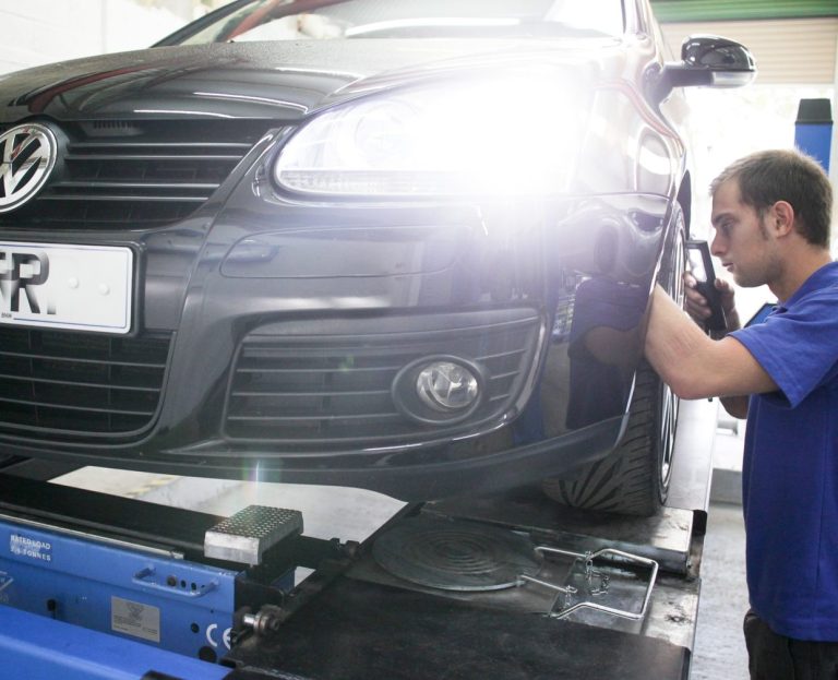 A vehicle technician working on the wheel of a car