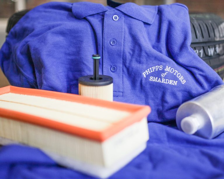 A Phipps Motors branded t-shirt, with servicing equipment such as air filters artfully positioned on top 