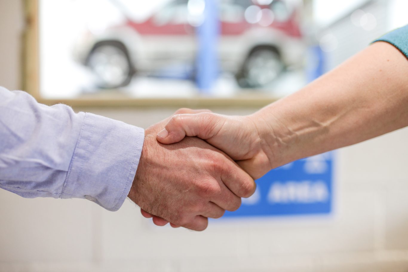 Friendly customer service team member shaking hands with a happy customer at Phipps Motors